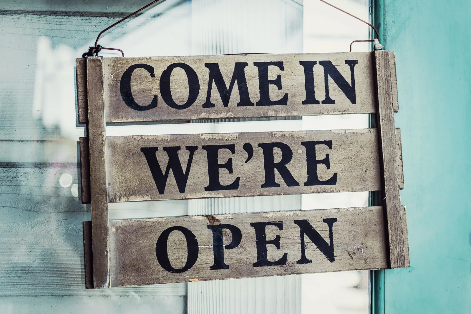 Wooden sign on a shop door reading Come in, we're open
