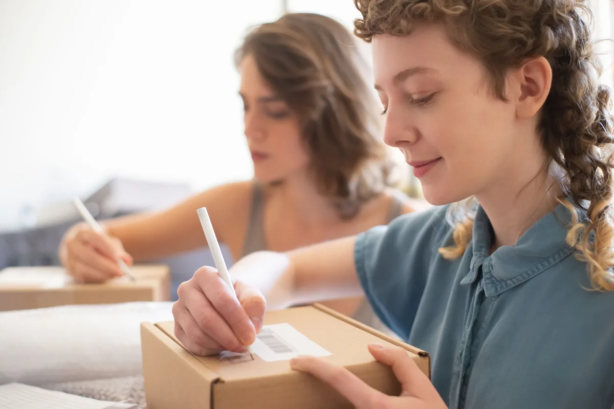 Two people labeling and packing boxes for customer orders