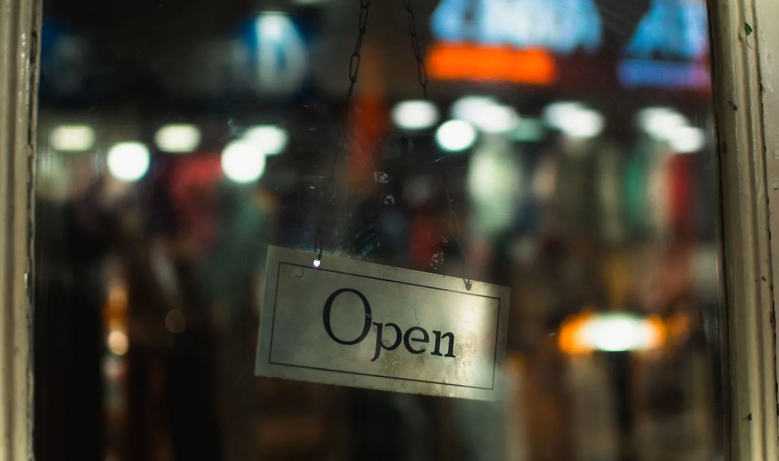 Small shop entrance at dusk with an open sign in the window